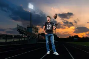 Blooming Prairie High School senior posing on the football field during a cinematic senior portrait session in Minnesota.