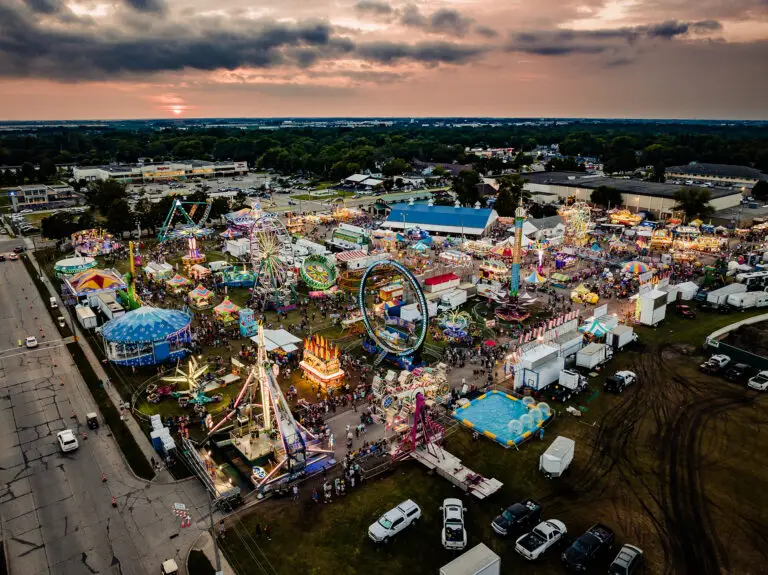 FAA Part 107 drone photograph overlooking the Steele County Free Fair midway with carnival rides, food vendors, and crowds in Owatonna, Minnesota.